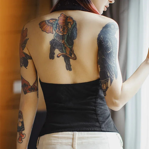Person with tattoos on their back and arms, wearing a black top.